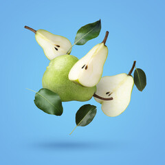 Fototapeta na wymiar Fresh ripe pears and green leaves falling on light blue background