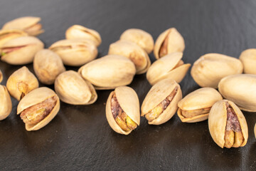 A few unshelled pistachios  on a slate stone, close-up.