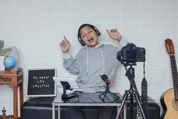Portrait of confident and creative Asian child singing on camera making music cover. Online influencer boy social media live steaming concept.