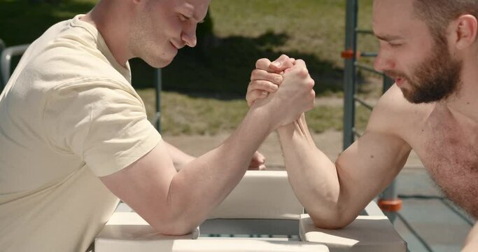 Two men engaged in arm wrestling in the park