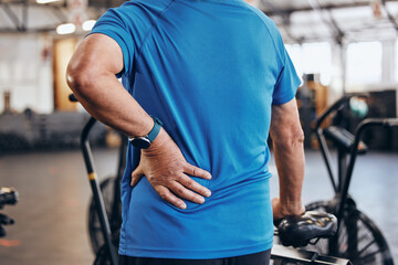 Sports, gym and old man with hand on back pain, emergency during workout at fitness studio. Health, wellness and inflammation, zoom on senior person hands on muscle cramps while training or exercise. - obrazy, fototapety, plakaty