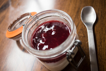 Cheesecake with red berries sauce served in a glass with different toppings.