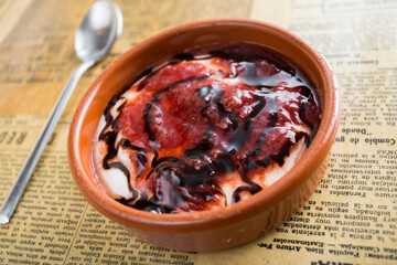Cheesecake with red berries sauce served in a glass with different toppings.