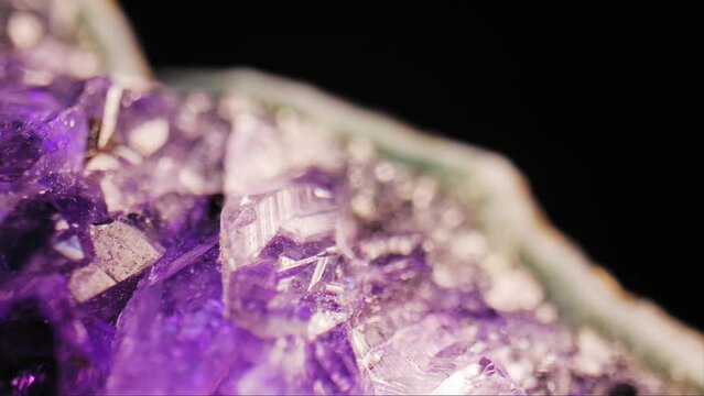 Stunning macro cinematic pan of purple amethyst crystal  lit against black background. Macro videography.