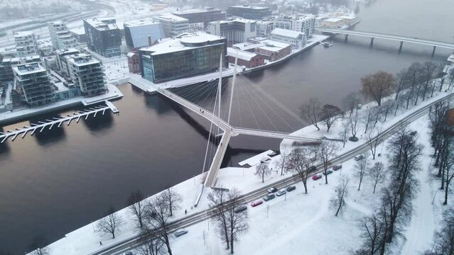 Circling around a beautiful pedestrian bridge over the river Drammenselva in town of Drammen, Norway during snowfall