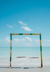 vista del mar azul , con unos columpios playeros en rpimer plano, en las playas de Brasil