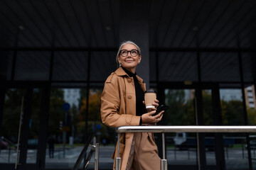 stylish businesswoman with cup of coffee outside - Powered by Adobe