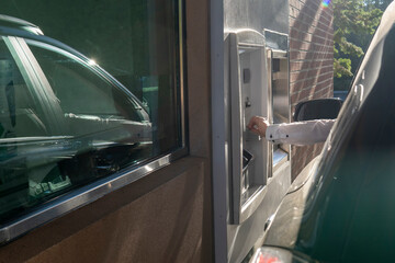 Man using - ATM drive through. Man's hand from the car with card near ATM. Money withdrawal