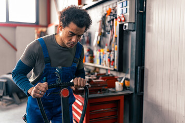 A mixed race worker in overalls pulls a small forklift for transport