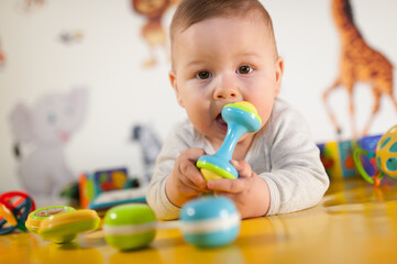 Cute baby boy nibbles and eats colourful toys because her small new teeth grow. Playground for babies