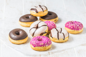 Colorful Donuts, Berliner, Krapfen with sugar icing and chocolate on white wooden background, vertical with copy space