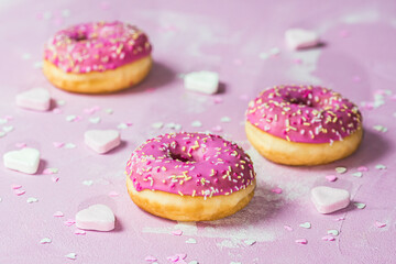 Donuts, Berliner, Krapfen with pink sugar icing on pink textured background, decorated with pink...