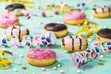 Donuts, Berliner, Krapfen with streamers and confetti. Colorful picture of carnival, birthday and fasching, green background