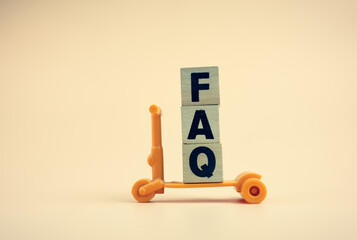 Close-up shot of wooden blocks with word FAQ on cream colour background. Frequently asked question concept