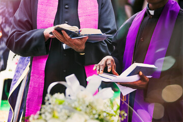 two priests reading prayers from the bible at a funeral