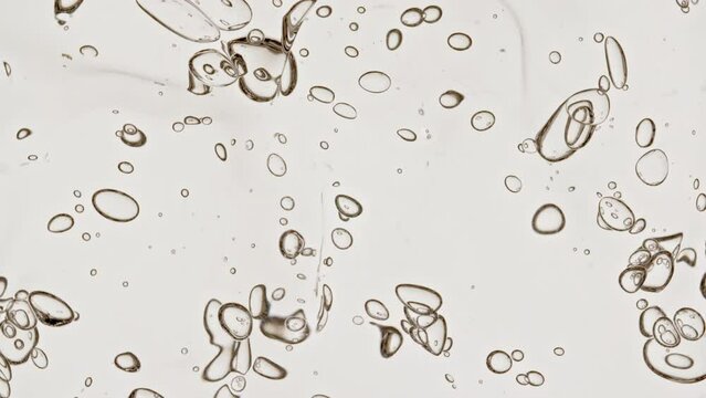 Transparent Cosmetic Gel Fluid With Molecule Bubbles and Oil Distribution on a White Background. Macro Shot of Natural Organic Cosmetics, Medicine. Production Close-up. Slow Motion. High quality 4k