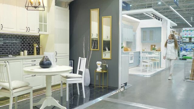 Modern kitchen on sale in a furniture store. A young mother with 5 years old girl daughter in a furniture store chooses a new kitchen set. Buying furniture for a new home. Home interior design ideas