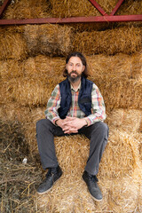 Naklejka na ściany i meble Bearded adult caucasian farmer in the hayloft. 