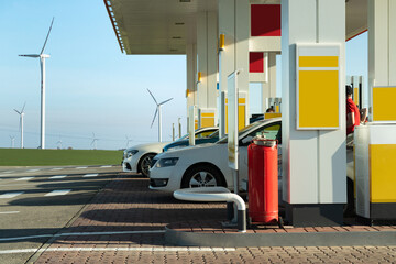 Cars on a gas station with wind turbines on a background