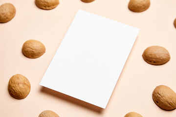 Blank card mockup with walnut shells and envelop on beige background. White holiday card mock up...