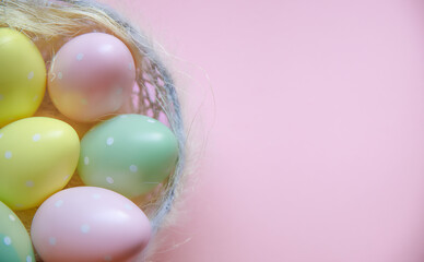 Easter eggs in a wicker basket on a pink background. Delicate tones. Background. Empty space for text. Easter holiday concept.
