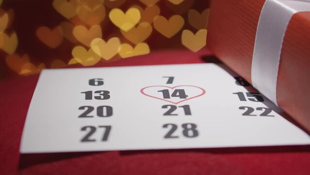 A gift for Valentines Day. Gift box on a red background with hearts. On the calendar, February 14 is the celebration of the event. Heart valentines. Romantic Valentine's Day in a cozy atmosphere.