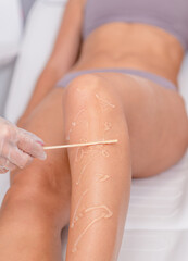 Beautician applying gel on female leg before epilation. Cosmetologist preparing woman skin for laser hair removal treatment in cosmetology clinic