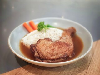 Grilled Chicken with Rice Garnished with Carrots and Long Beans  Topped with sauce placed on a ceramic plate.