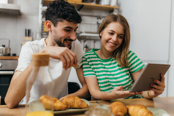 Young couple reading news in the kitchen