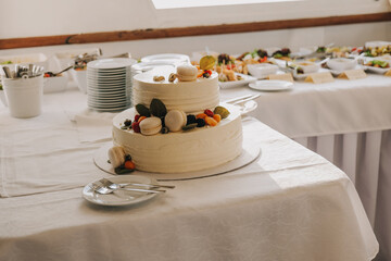 Wedding cake with macarons and fruits on the buffet table