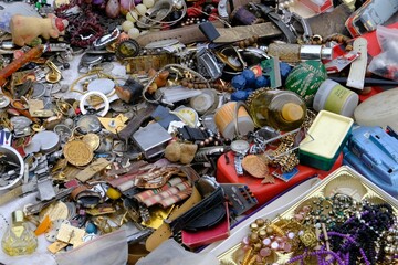 Various things on the counter of the flea market, jewelry and various containers of perfume.
