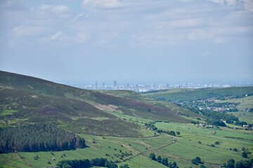 Naklejka premium View from the top of a mountain with green fields and a blue sky background. Taken in Oldham England. 