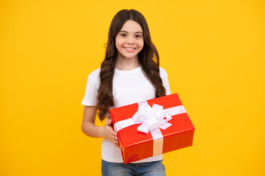 Happy Teenager, Positive And Smiling Emotions Of Teen Girl. Teenager Child In T Shirt Holding Gift Box On Yellow Isolated Background. Gift For Kids Birthday. Summer Holiday.