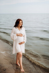 pregnant girl with brown hair on the seashore