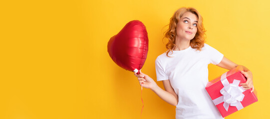 smiling pondering redhead woman with red heart balloon and gift box. be my valentine. Beauty woman isolated face portrait, banner with mock up copy space.