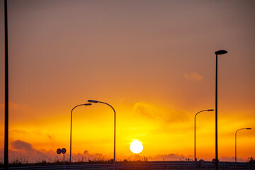 夕日にうかぶ道路照明灯のシルエット