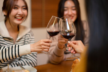 Young smiling woman drinking and clinking glass of wine to toasting with happiness while celebrating in new year party at home