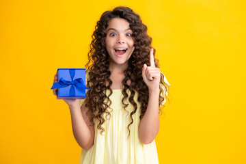 Excited teenager, glad amazed and overjoyed emotions. Teenager child holding gift box on yellow isolated background. Gift for kids birthday. Christmas or New Year present box.