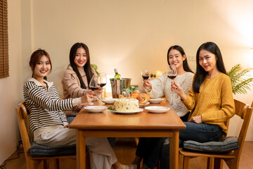 Young smiling woman drinking and clinking glass of wine to toasting with happiness while celebrating in new year party at home