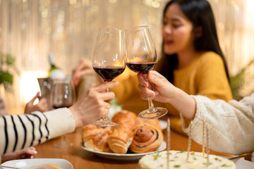 Young woman drinking and clinking glass of wine to toasting with happiness while celebrating in new year party at home