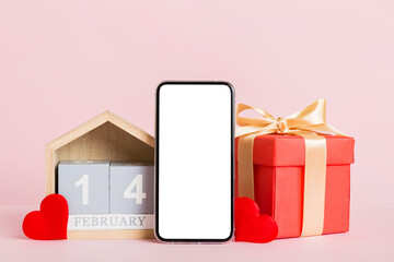 mobile phone with blank screen on colored background with hearts, calendar and gift box, valentine day 14 february concept perspertive view flat lay