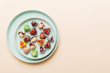 Plate with different chocolate on colored background. Assortment of fine chocolates top view vith copy space Health and obesity concept