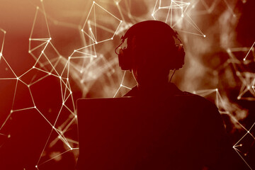 The silhouette of a military man in headphones at a laptop against a glowing background of a tangle of lines and dots, contour lighting. Concept: information gathering, surveillance and control. - obrazy, fototapety, plakaty
