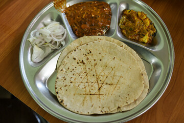 Making or cooking tawa roti Aloo Paratha. Indian potato stuffed flatbread with butter on top. Served with fresh sweet Lassi chutney and pickle. Street food in Kullu Manali Himachal Pradesh India.