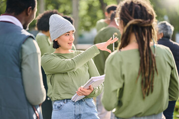 Volunteer schedule, community cleaning leader and charity service outdoor with Asian woman talking. Recycle team, collaboration and eco friendly female manager giving recycling teamwork orders - obrazy, fototapety, plakaty