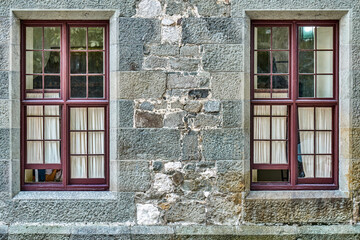 Old windows with white curtains on stone wall of historical building. Medieval castle with restored brick walls attracts arriving visitors attention © timltv