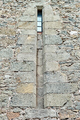 Old medieval window surrounded by stone wall in castle attracts tourists attention. Historical exterior illuminated by bright sunlight © timltv