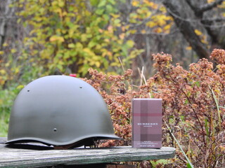 Fototapeta premium Bottle of Burberry London eau de toilette with a 1960s steel helmet and other Russian militaria, Taldom, Russia - October 31, 2020