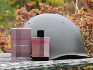 Obraz premium Bottle of Burberry London eau de toilette with a 1960s steel helmet and other Russian militaria, Taldom, Russia - October 31, 2020