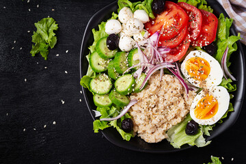 Healthy breakfast. Savory oatmeal with fresh cucumber, tomatoes, olives, lettuce, mozzarella cheese and boiled egg. Top view